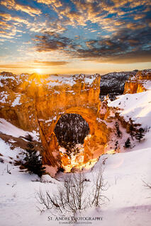 Bryce Natural Bridge back lit by the rising sun. The arch is covered with snow as it was taken in the winter