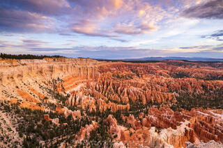Bryce Point in Bryce Canyon National Park at sunrise. The hoodoos are gently lit up and the clouds are soft pastel colors