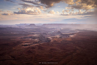 Green river overlook. A large canyon expands below the viewer with a large river cutting through the desert. A thunderstorm is raining in the image. 