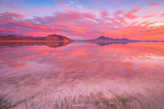 The salt flats in western utah are covered in a layer of water allowing for dramatic reflected light from a colorful sunrise. 