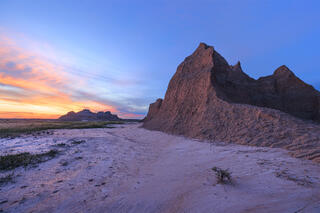 A pyramid of mud side lit by a stunning sunset of yellow, orange, and blue skies. 