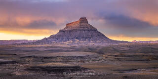 Factory butte in Southern Utah at sunset as a snow storm settles in. Dramatic light lights up the clouds. 