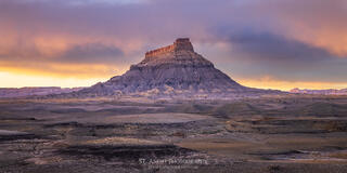 Factory butte in Southern Utah at sunset as a snow storm settles in. Dramatic light lights up the clouds. 