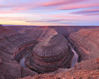 A large canyon creating a geological feature called a gooseneck. The San Juan River quietly flows at the bottom of the canyon.