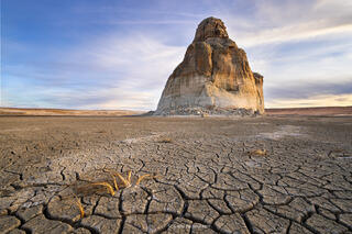 Lone rock at lake powell stands dry in a field of dried mud cracks. 