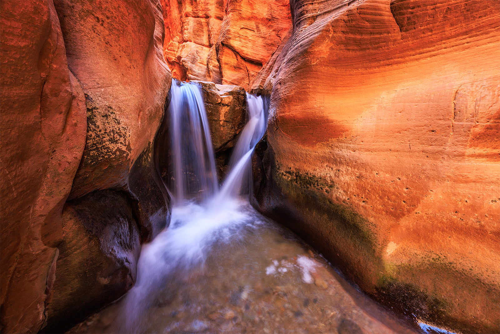 Kanarraville falls in fall with light illuminating the canyon and water flowing off of a short fall.