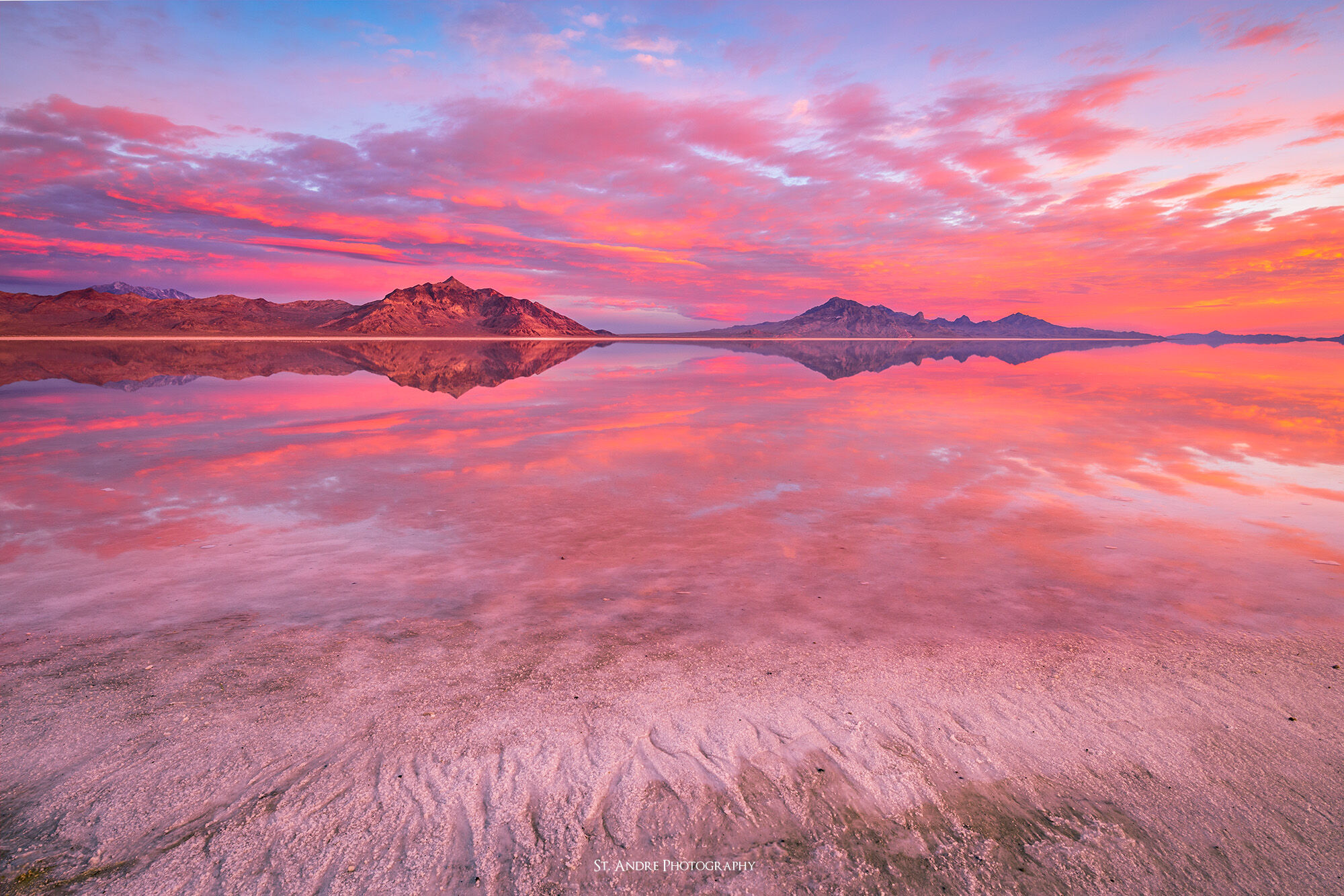 The salt flats in western utah are covered in a layer of water allowing for dramatic reflected light from a colorful sunrise.