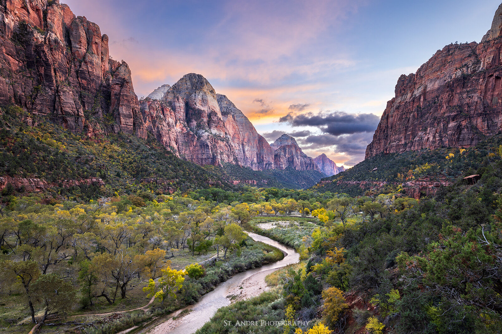 A view of the Temple of the Sun mountain in Zion National Park with the virgin river leading the viewer through the image with fall leaves on the canyon floor